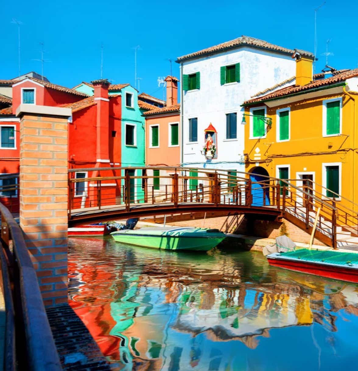 Uno scorcio dell'incantevole isola di Burano, con vista sulle caratteristiche case colorate e un ponte che collega due sponde di un rio.