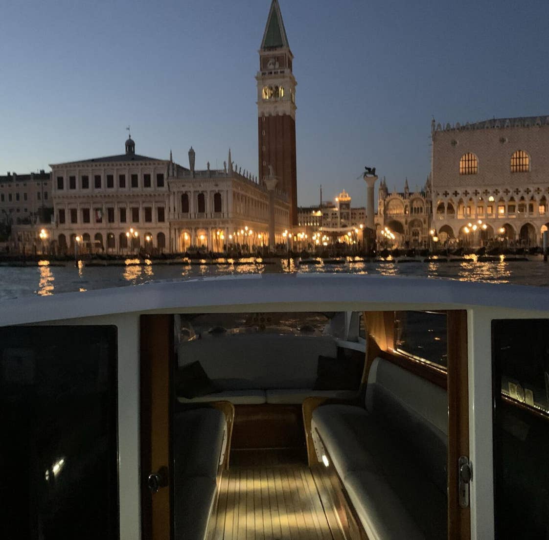 Vista di piazza san marco all'imbrunire, dal nostro motoscafo fermo in mezzo alla laguna. Nonostante ci sia ancora un po di chiaro, Piazza San Marco è già illuminata dalle luci.
